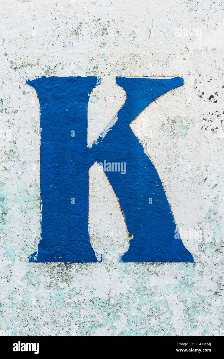 Blue letter K painted on a peeling wall Stock Photo
