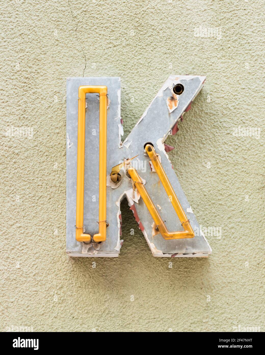 Yellow neon letter K on yellow-green wall Stock Photo