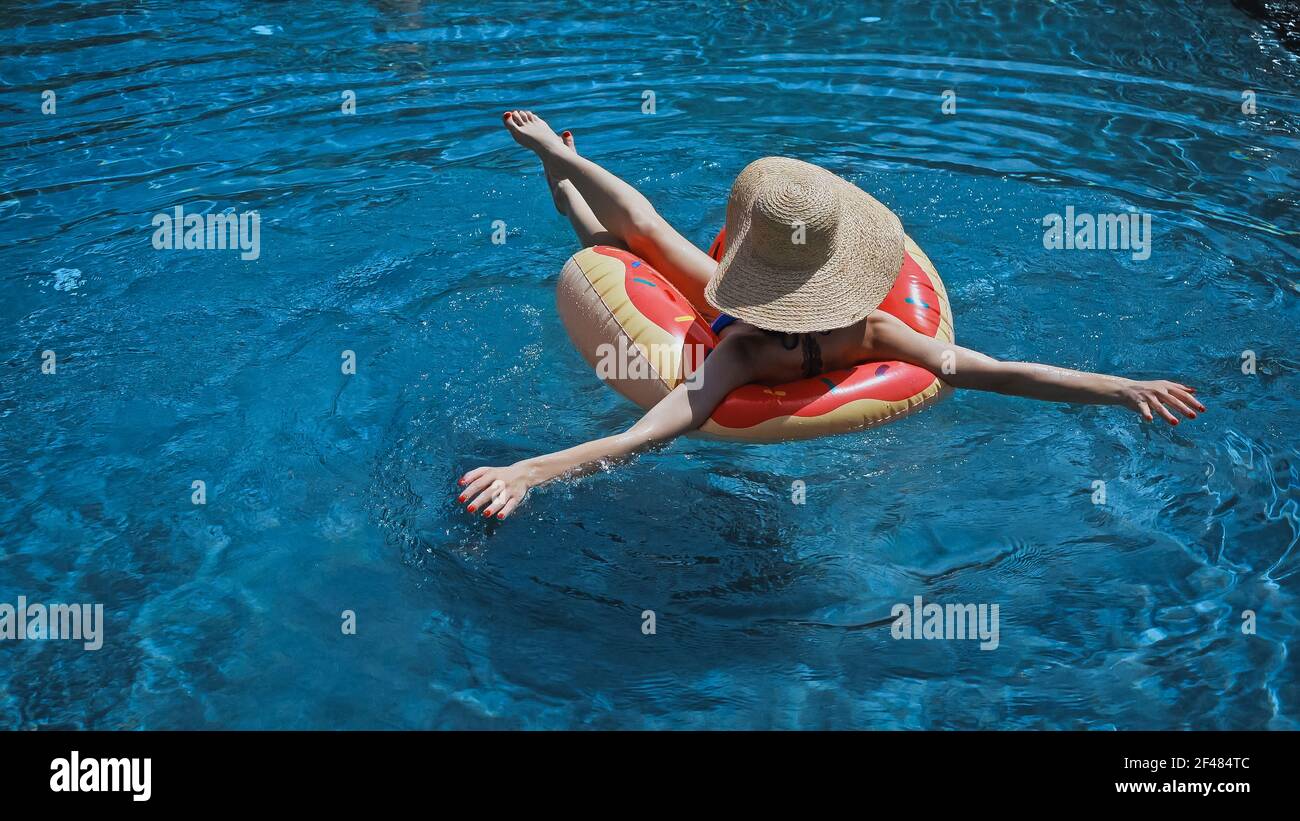 back view of woman in straw hat swimming in pool with swim ring Stock ...