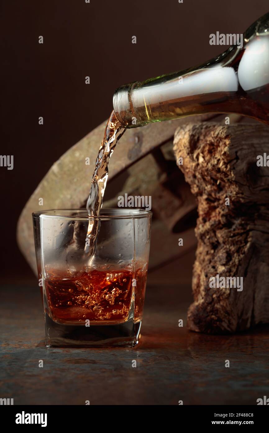 https://c8.alamy.com/comp/2F488C8/whiskey-is-poured-from-a-bottle-into-a-frozen-glass-with-natural-ice-rough-rusty-background-2F488C8.jpg