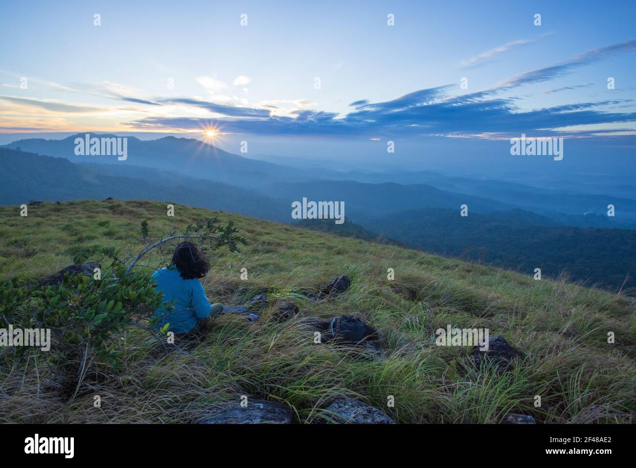 A lady enjoying the magnificent view from a hilltop in Wayanad during early morning (image taken in Wayanad, Kerala) Stock Photo