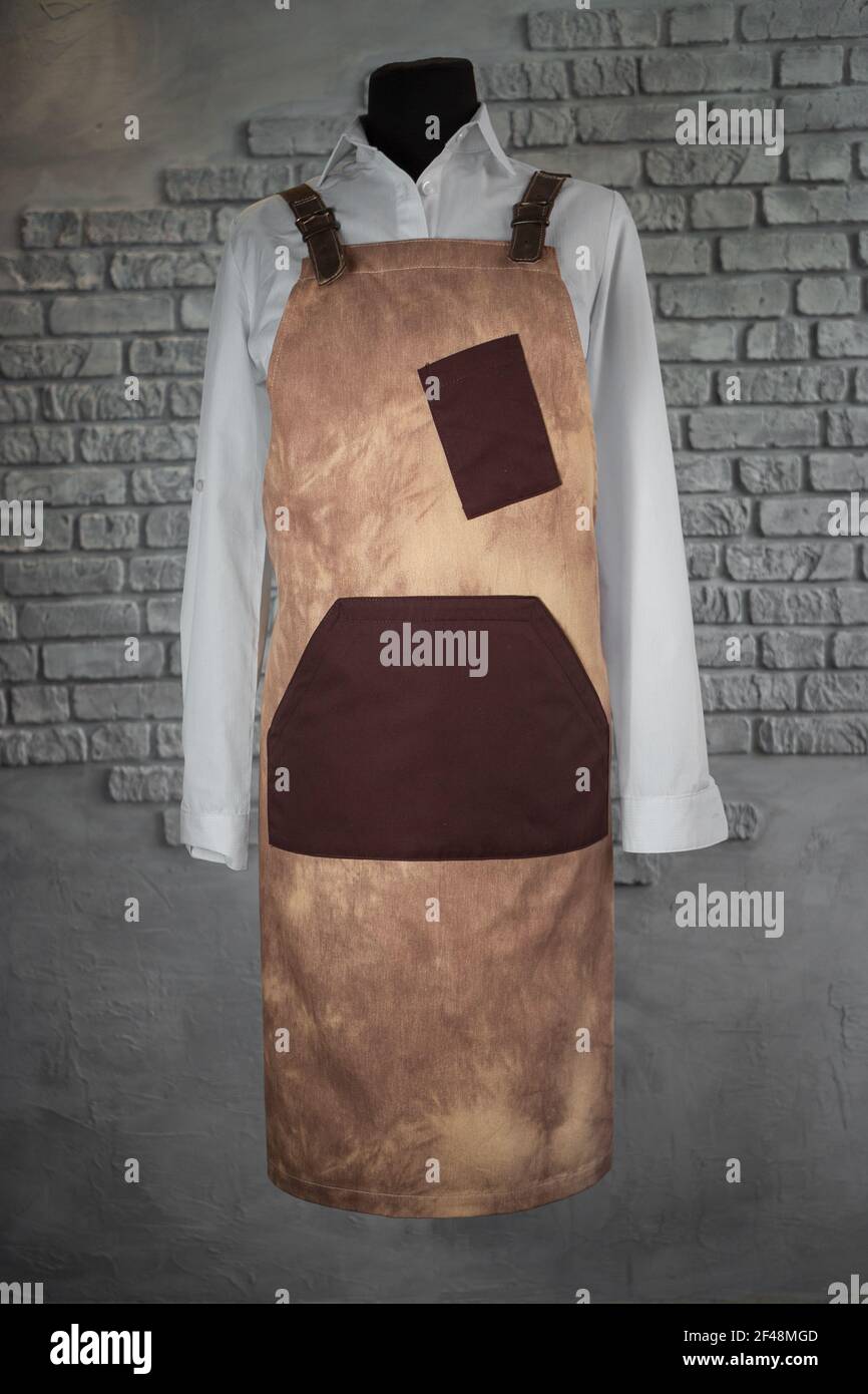 Cream apron, with leather inserts, for staff on a mannequin, on a gray background. Uniform. Stock Photo