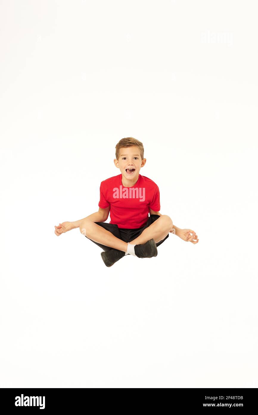 Adorable sporty boy jumping and doing yoga exercise Stock Photo