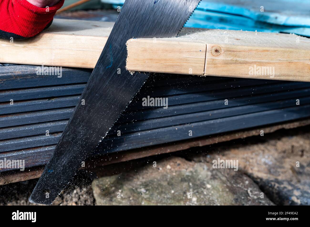 Close up of hand saw cutting through wooden beam. gazebo roof construction. Stock Photo
