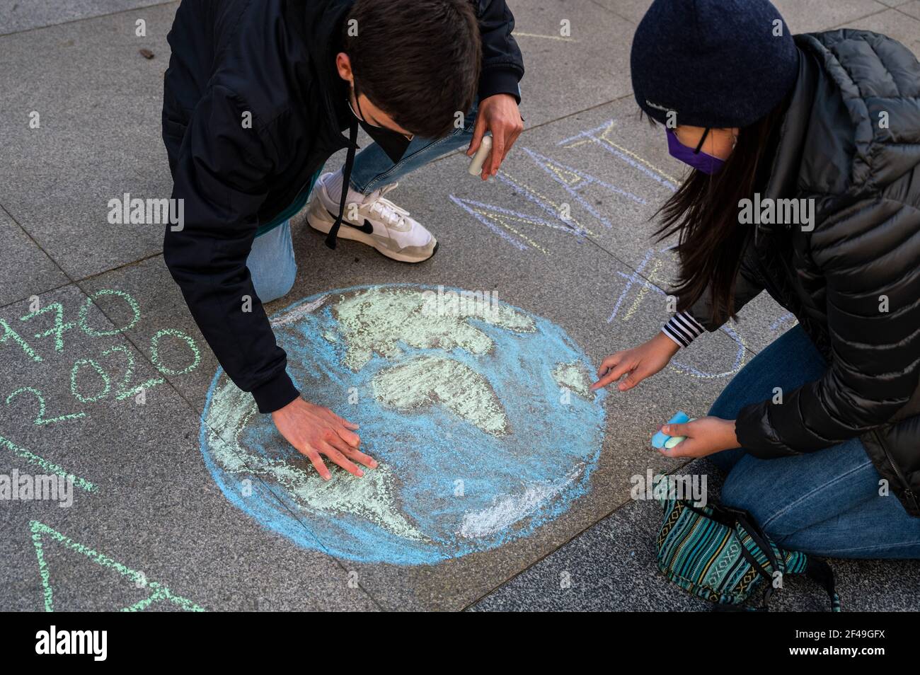Madrid, Spain. 19th Mar, 2021. Climate change activists of 'Fridays for Future' group painting the Earth with chalks during a protest in front of the Spanish Parliament calling for action in climate policies since it has been 5 years from the Paris Agreement on Climate Change and global temperature of the planet keeps rising. Credit: Marcos del Mazo/Alamy Live News Stock Photo