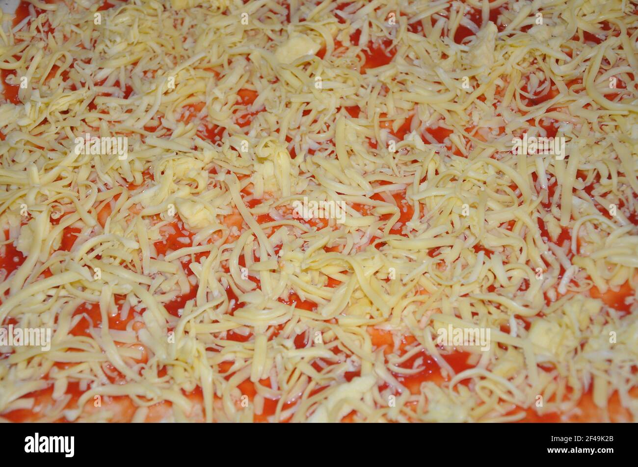Background texture of unbaked mozzarella on a pizza. Image of unbaked pizza with ham and chees, close-up Stock Photo