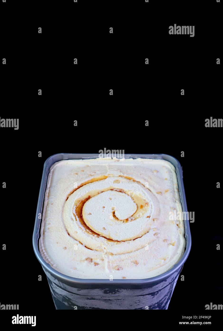 Tub of Delicious Salted Caramel Macadamia Nut Ice Cream Isolated on Black Background Stock Photo