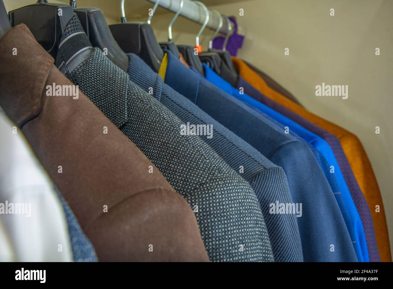 Wardrobe with suits of different colors in close-up Stock Photo