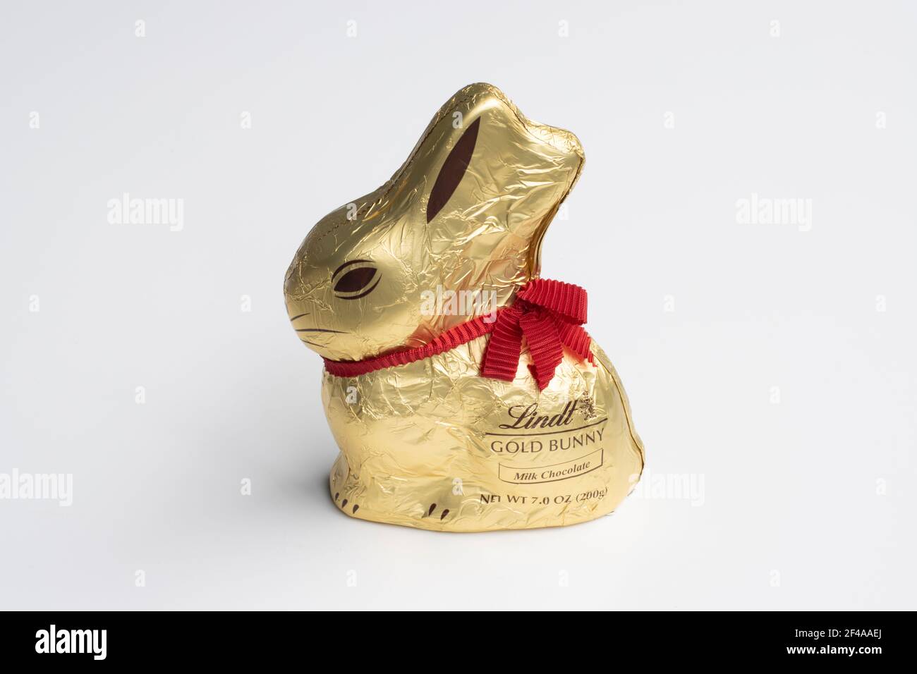 Lindt Gold Bunny isolated on a white background. Milk chocolate Easter bunny wrapped in golden foil with a red ribbon, produced by Lindt, a Swiss ... Stock Photo