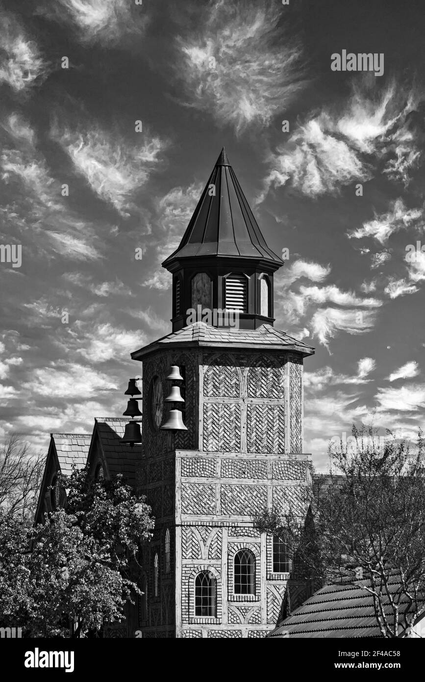 Black and white, building with bells, belfry against sky with white fluffy clouds. Stock Photo
