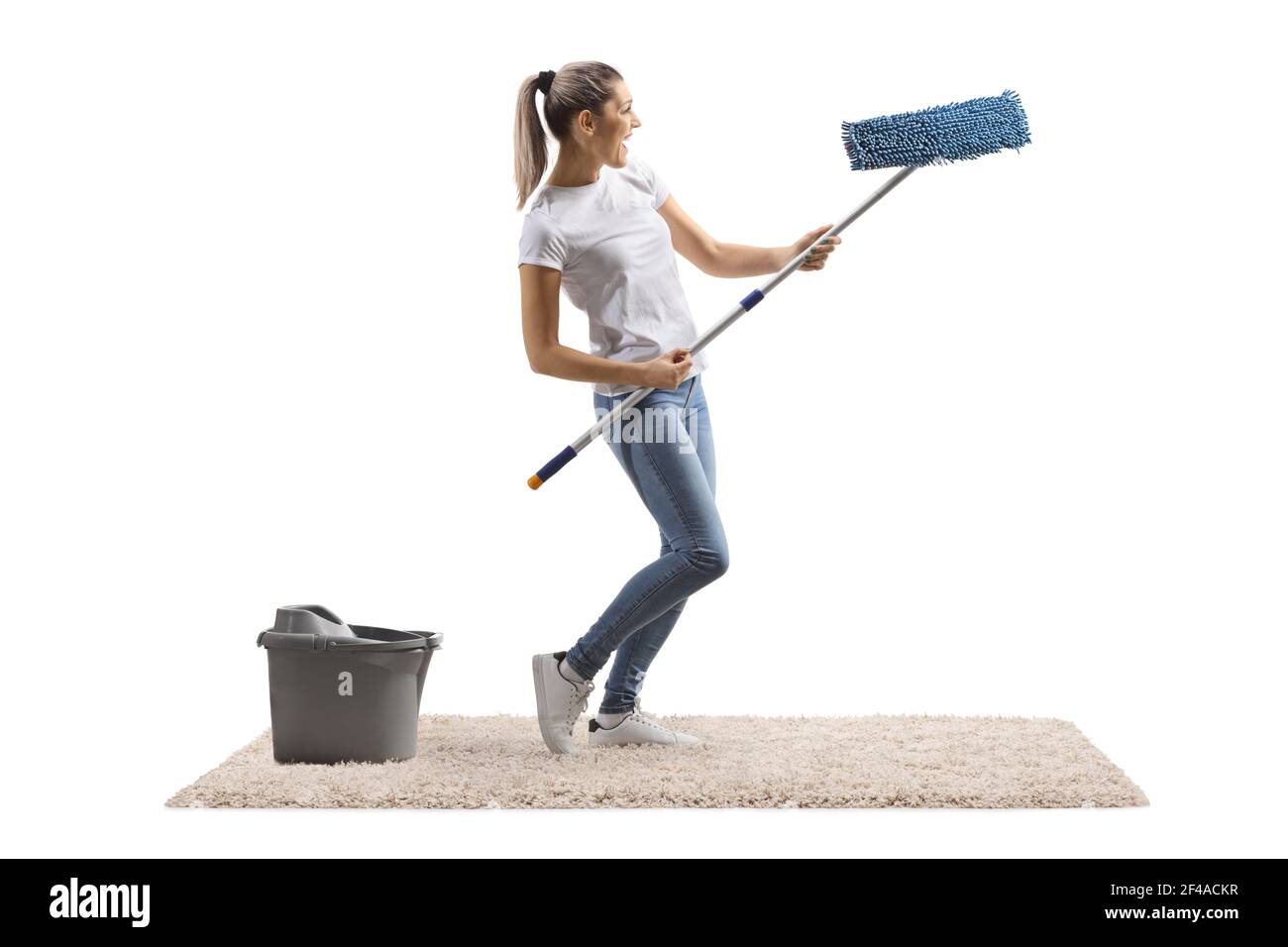 Young woman on a carpet dancing with a cleaning mop isolated on white background Stock Photo