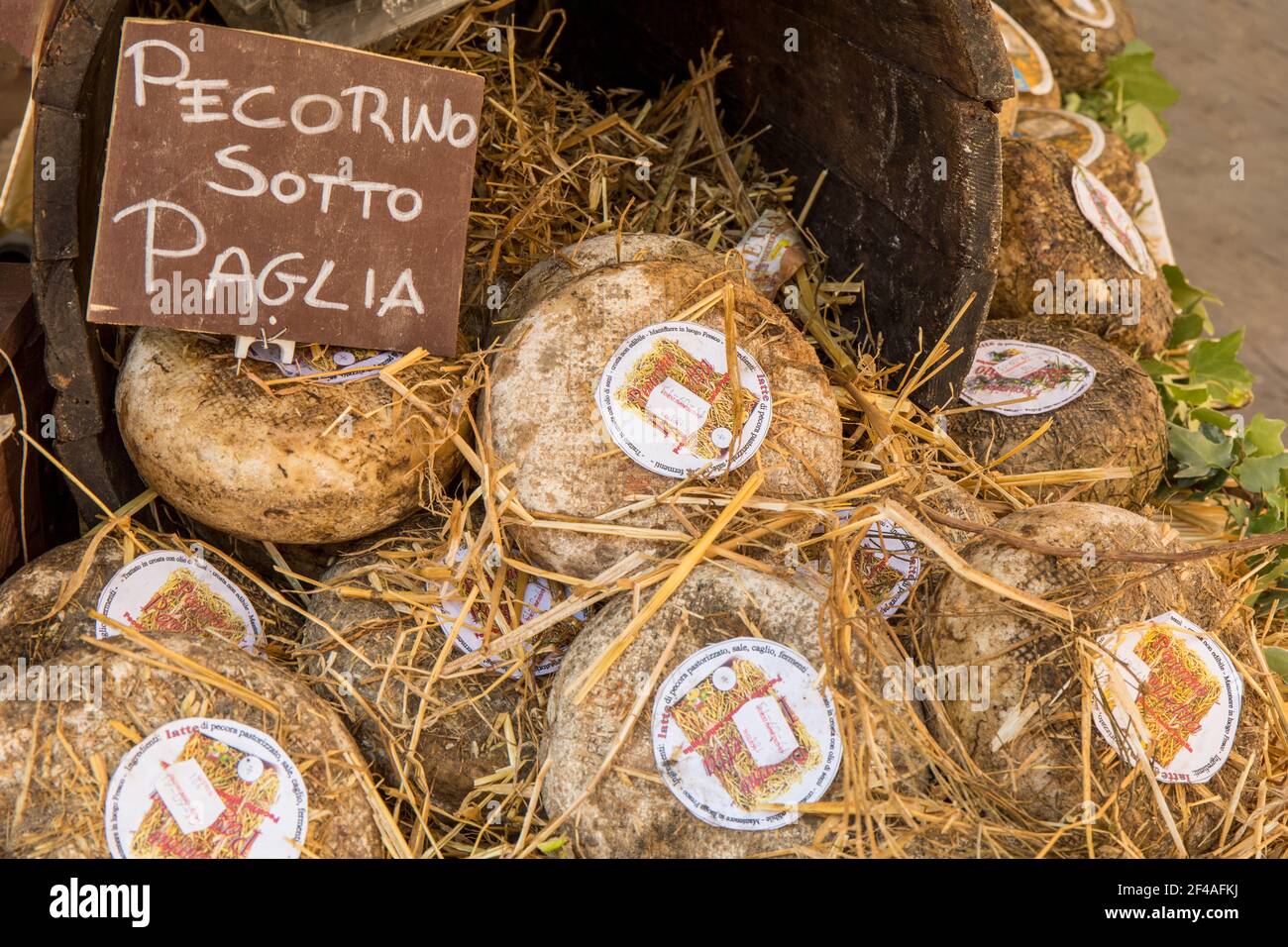Cortona, Italy.  Pecorino Sotto Paglia cheese rounds aged under straw for sale at an outdoor market. Stock Photo