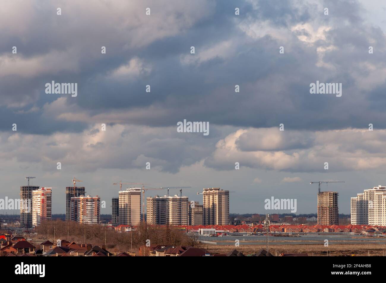 Krasnodar, Russia - March 18 2021: Cloudy skies in the spring, New high-rise buildings under construction, tower cranes Stock Photo