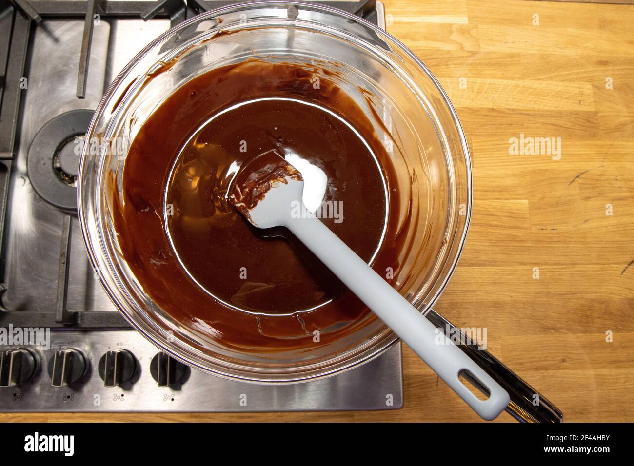 A glass bowl of melted chocolate being melted on a stove in a kitchen
