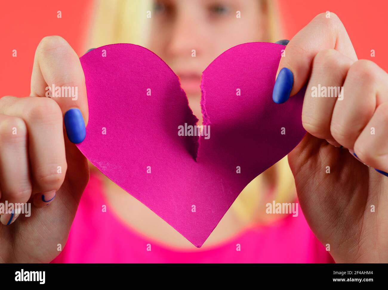 Broken heart. Woman tearing heart in half. Divorce, parting, separation. Relationship problem. Break of relationships. Stock Photo