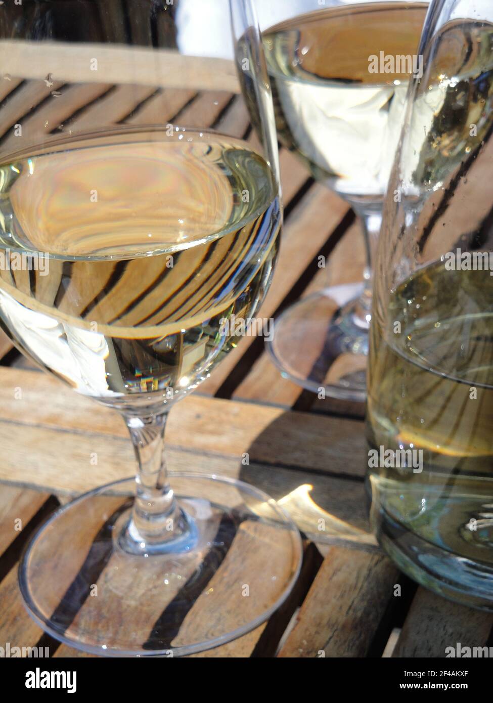 A vertical shot of a glass cup and bottle filled with white wine placed on  a wooden table Stock Photo - Alamy