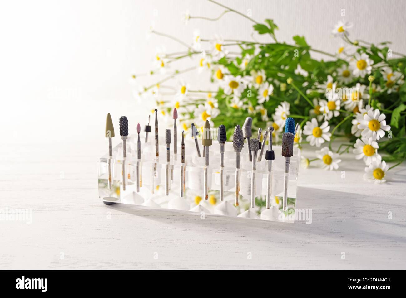 Cosmetic grinding and polishing tools for beauty and health care treatments such as manicure and pedicure in a transparent holder, blurry flowers in t Stock Photo