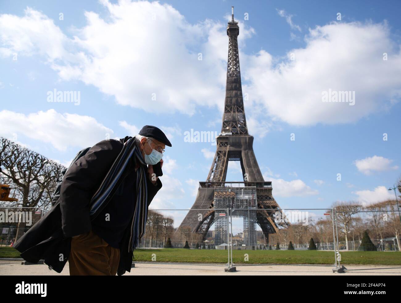 Paris, France. 19th Mar, 2021. A man wearing a face mask walks in the Champ de Mars in Paris, France, on March 19, 2021. French Prime Minister Jean Castex on Thursday announced 'new massive measures' to curb COVID-19 in the country's 16 worst-hit regions, including Paris. Starting Friday midnight, about 18 million French people in regions such as Paris, Hauts-de-France in the north as well as the Alpes-Maritimes on the Mediterranean should stay at home, Castex announced at a press briefing on the epidemic situation. Credit: Gao Jing/Xinhua/Alamy Live News Stock Photo