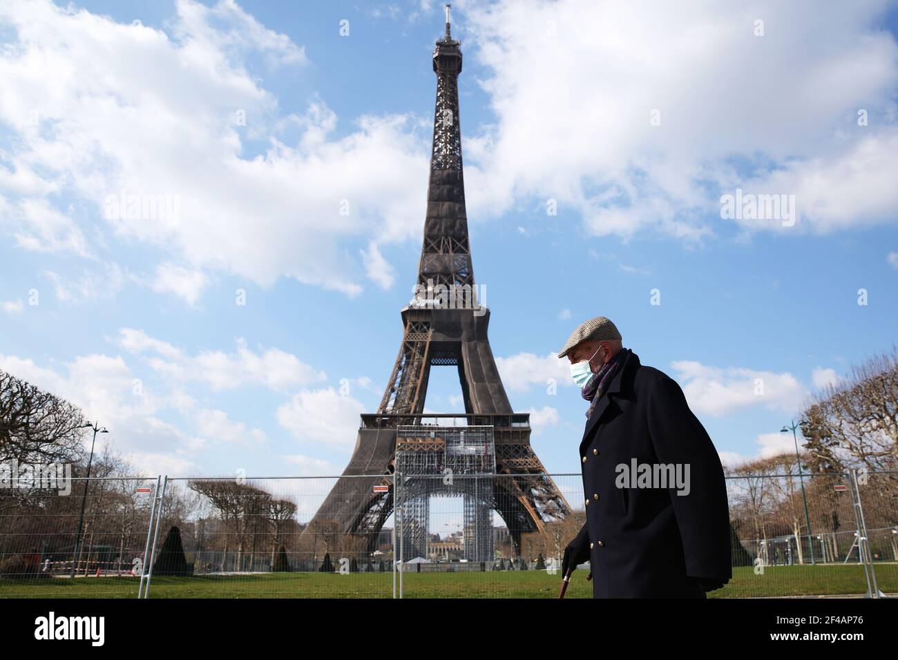 Paris, France. 19th Mar, 2021. A man wearing a face mask walks in the Champ de Mars in Paris, France, on March 19, 2021. French Prime Minister Jean Castex on Thursday announced 'new massive measures' to curb COVID-19 in the country's 16 worst-hit regions, including Paris. Starting Friday midnight, about 18 million French people in regions such as Paris, Hauts-de-France in the north as well as the Alpes-Maritimes on the Mediterranean should stay at home, Castex announced at a press briefing on the epidemic situation. Credit: Gao Jing/Xinhua/Alamy Live News Stock Photo