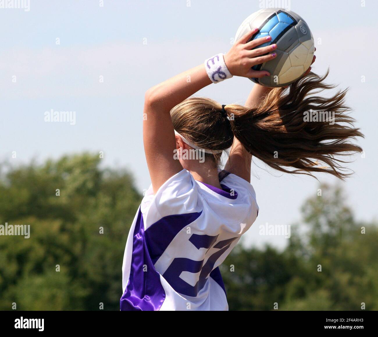 A soccer player throws in the ball from the sidelines with her ponytail flying Stock Photo Alamy