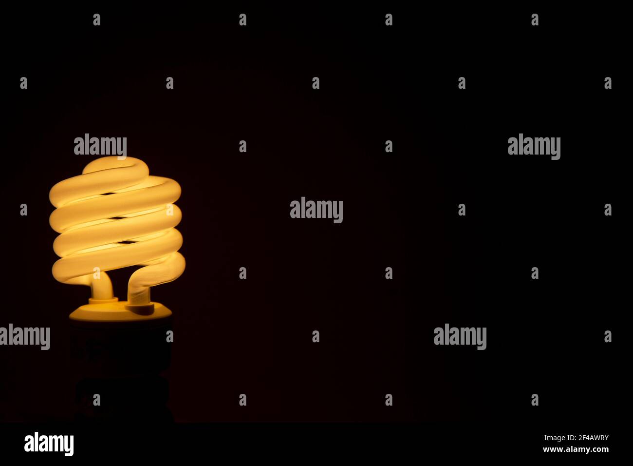 Energy efficient fluorescent glowing light bulb on dark background ...