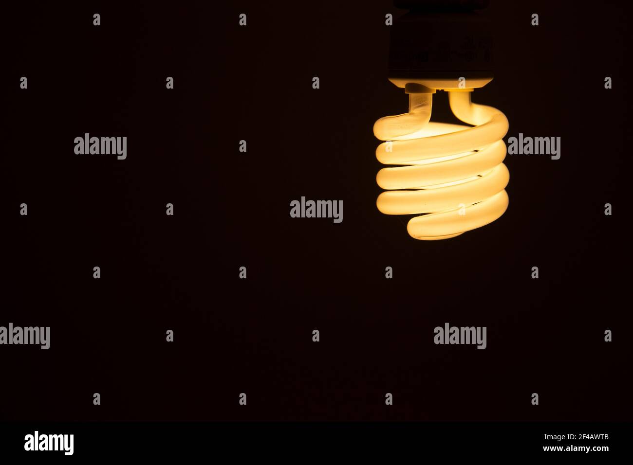 Energy efficient fluorescent glowing light bulb on dark background ...