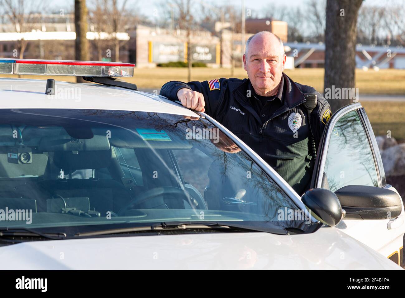 A Purdue University Fort Wayne police officer stands next to a patrol car on campus. Stock Photo
