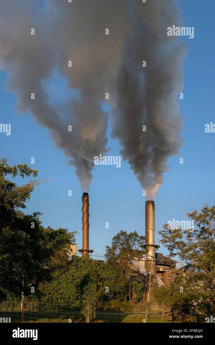 Emissions rise up out of two smoke stacks Stock Photo