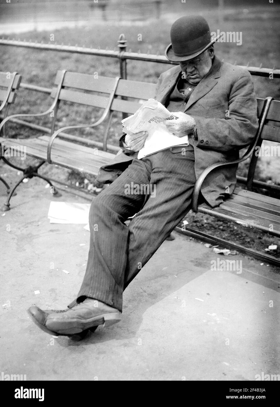 Man sitting on a park bench in Union Square, reading a newspaper ca. 1910-1915 Stock Photo