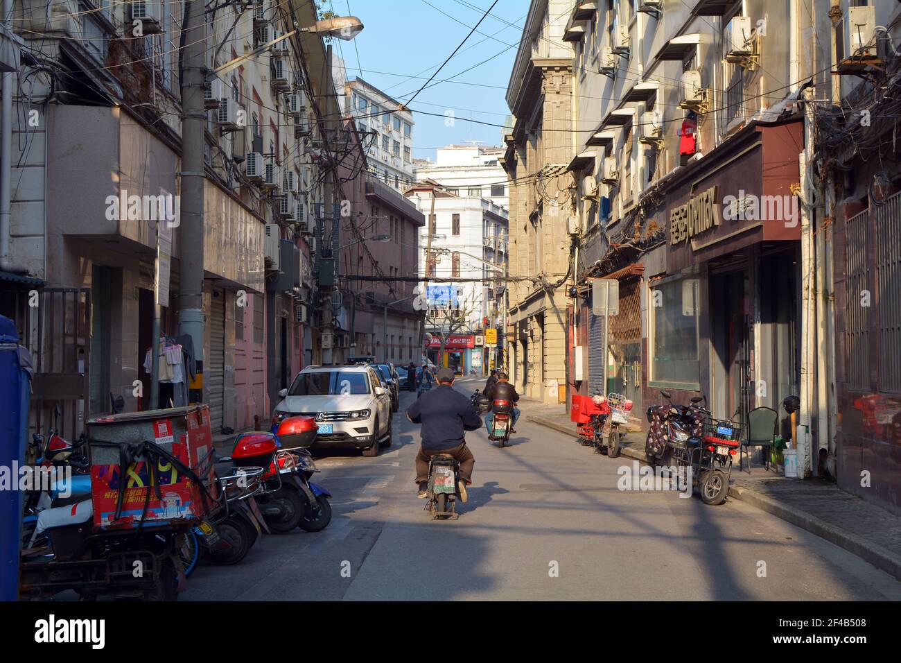 Scene from down town Shanghai, scooters and bikes going through an old street away from the tourist area. Stock Photo