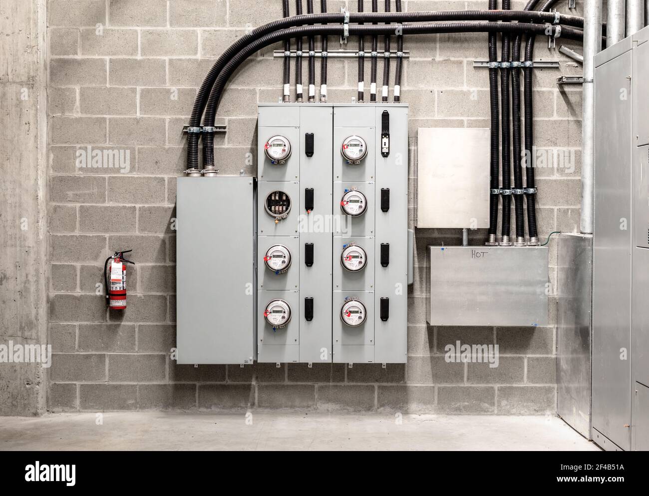 Electrical room with multiple smart meters, cabinets, wiring and fire extinguisher. Below-grade service room of 4 story strata building with residenti Stock Photo