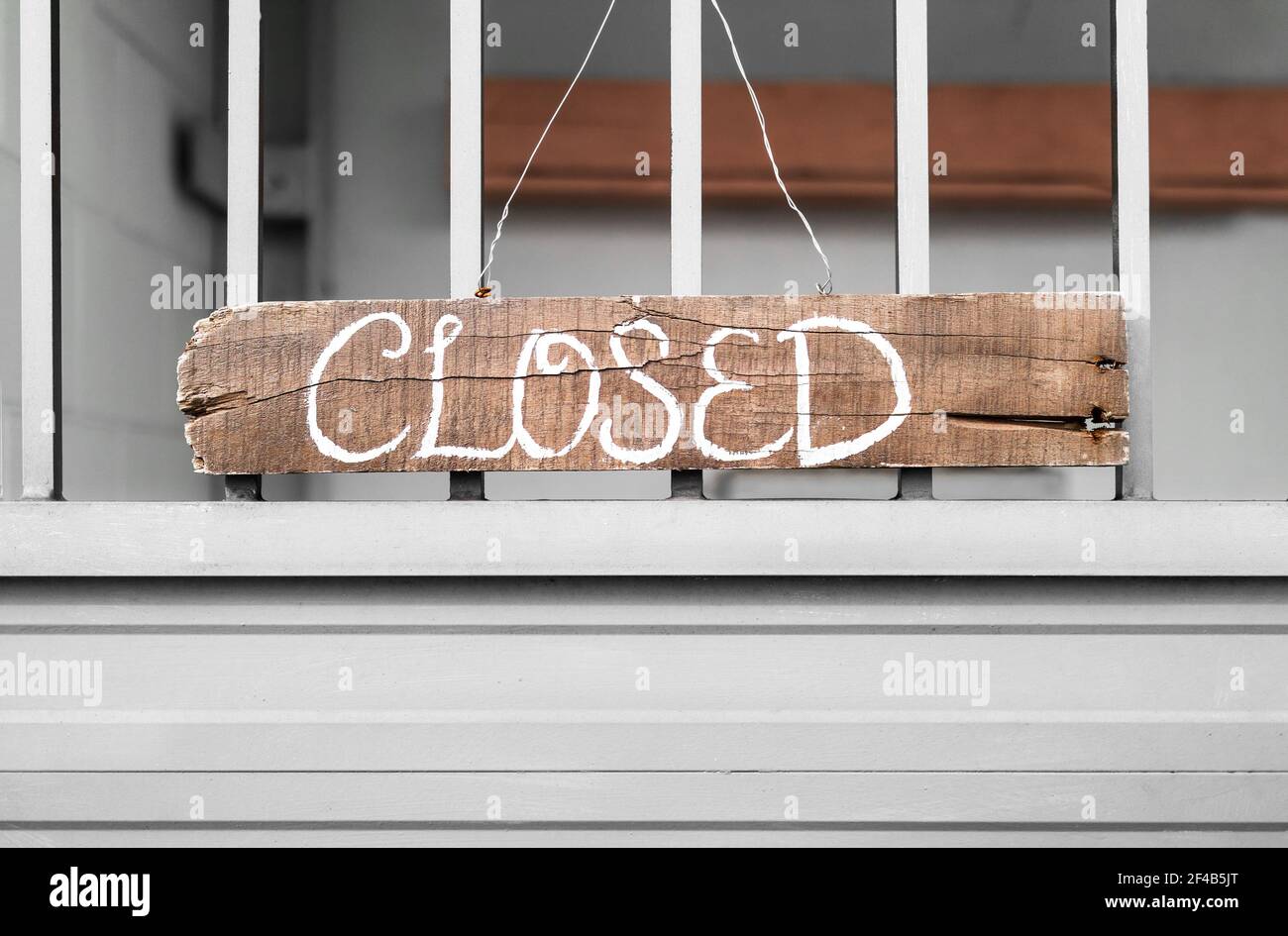 Closed sign. Handcrafted brown ragged wood sign with white handwritten letters. The signage hangs on a gate held with metal wires. Concept for busines Stock Photo