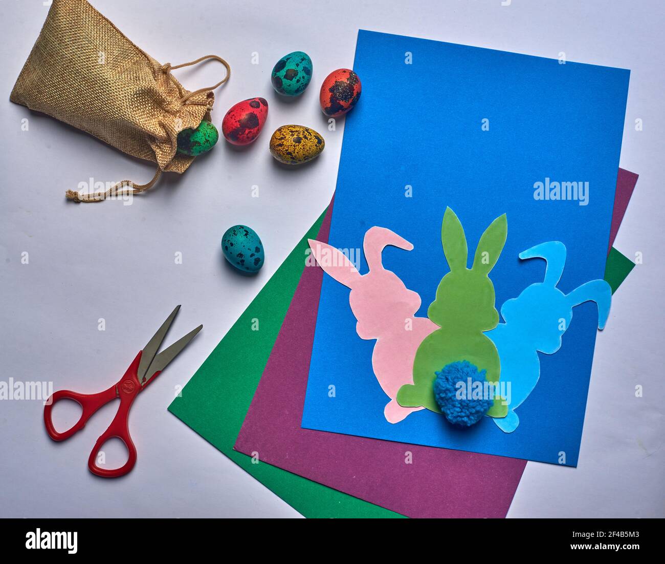 scissors on blue background easter hares with tail and eggs Stock Photo