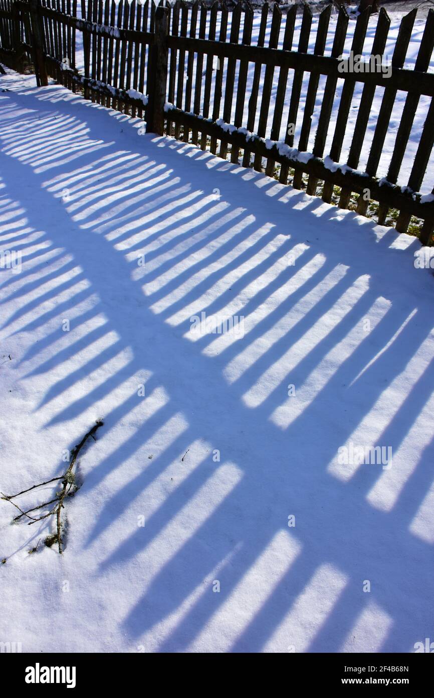 Wooden old fence shadow on winter snow Stock Photo - Alamy