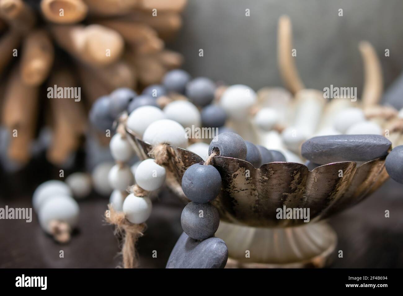 Wood pearls decoration on table, close up. Blue and white pearls draped over dish. Soft muted brown, green and blue colors. Decoration backdrop. Selec Stock Photo