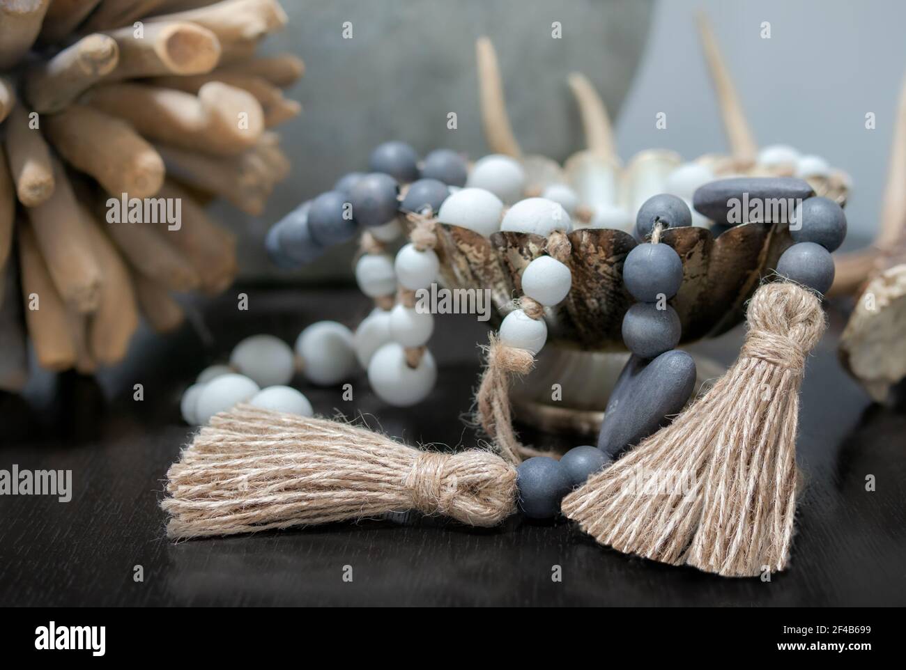 Arrangement of wood pearl necklaces draped over dish on table. Blue and white pearls. Muted brown, green and blue colors. Decoration backdrop. Stock Photo