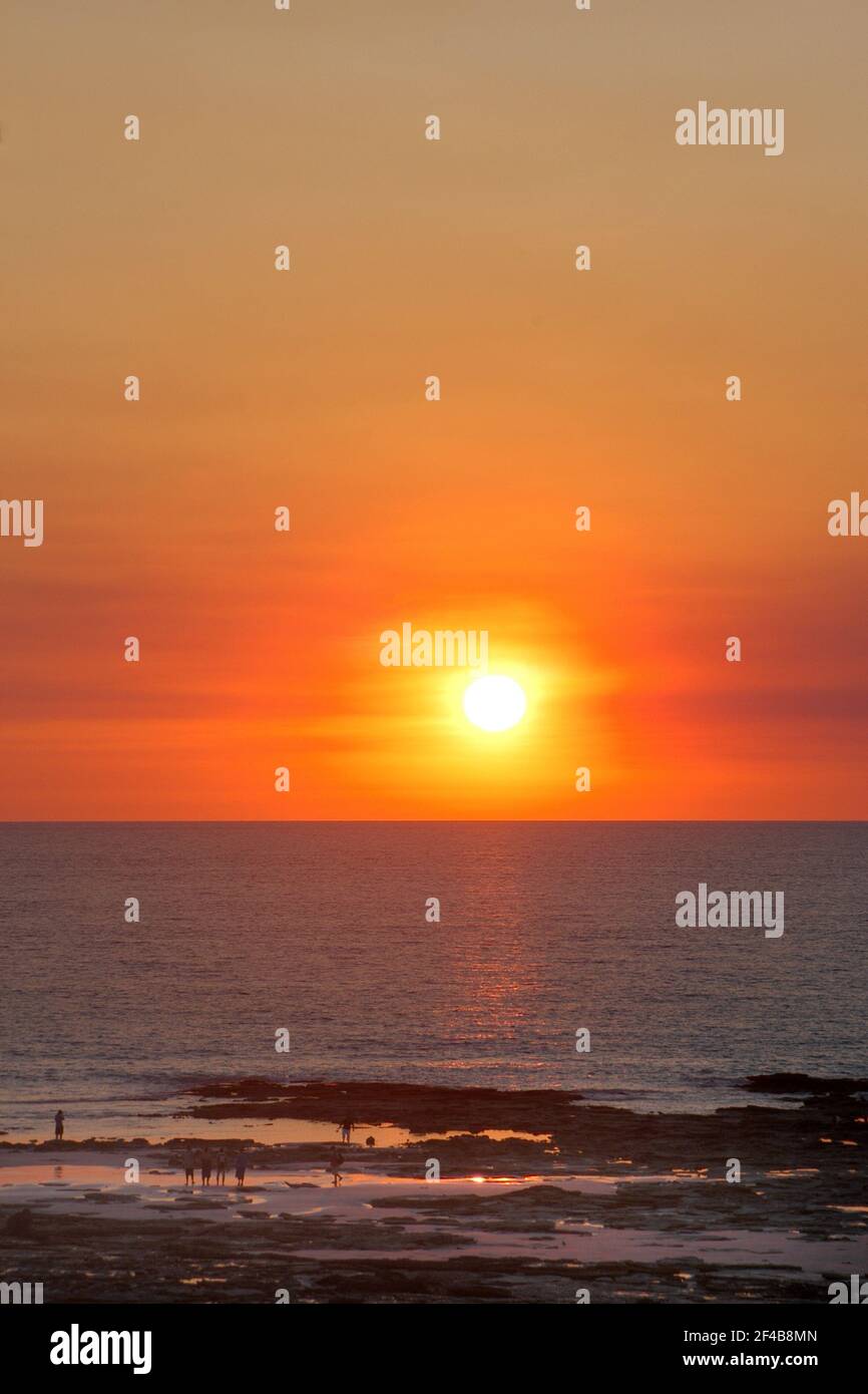 Distant view of silhouettes of people enjoying a dramatic golden sunset on Cable Beach at low tide, Broome, Western Australia. Stock Photo