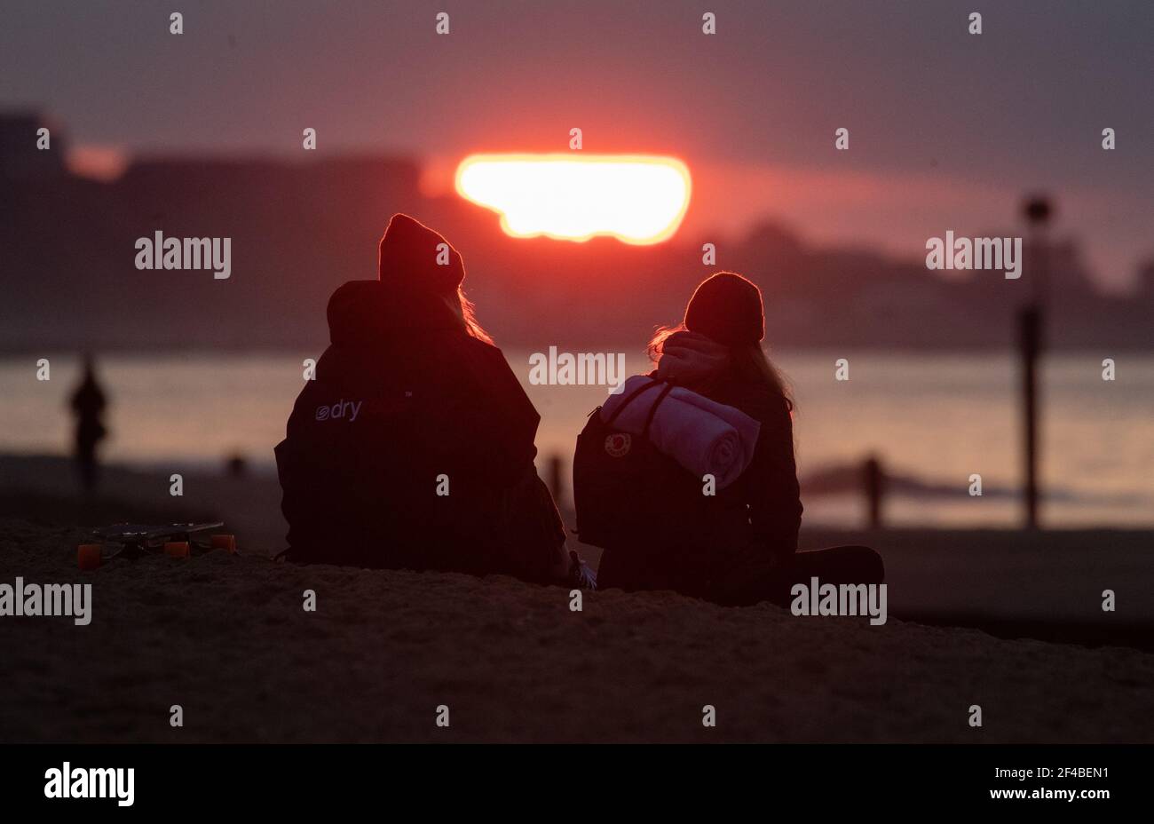 People watch the sun rise over Boscombe beach in Dorset on the day of the Spring equinox. Picture date: Saturday March 20, 2021. Stock Photo