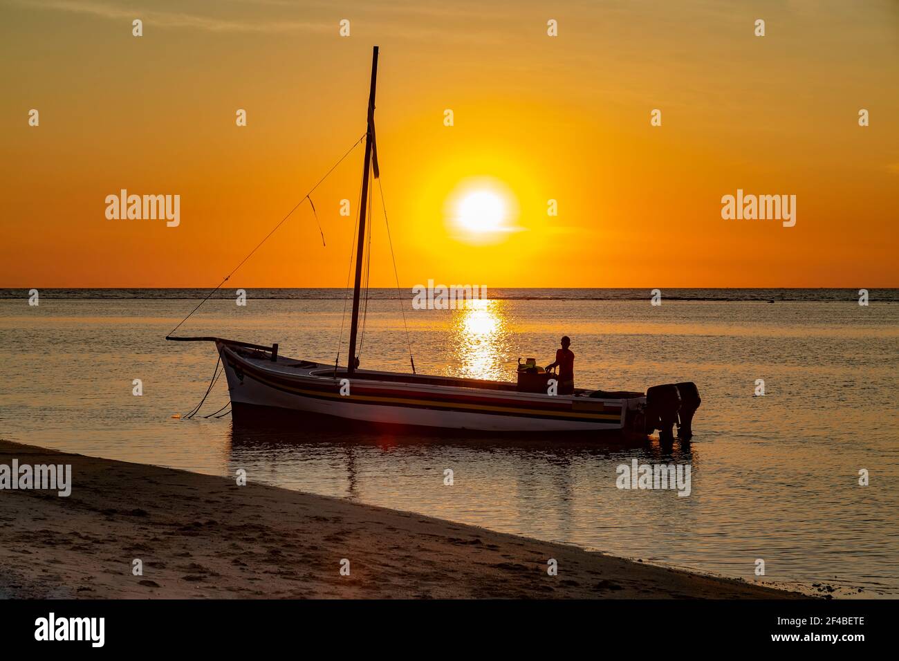 fishing boat at sunset on the public beach of Flic en Flac Stock Photo