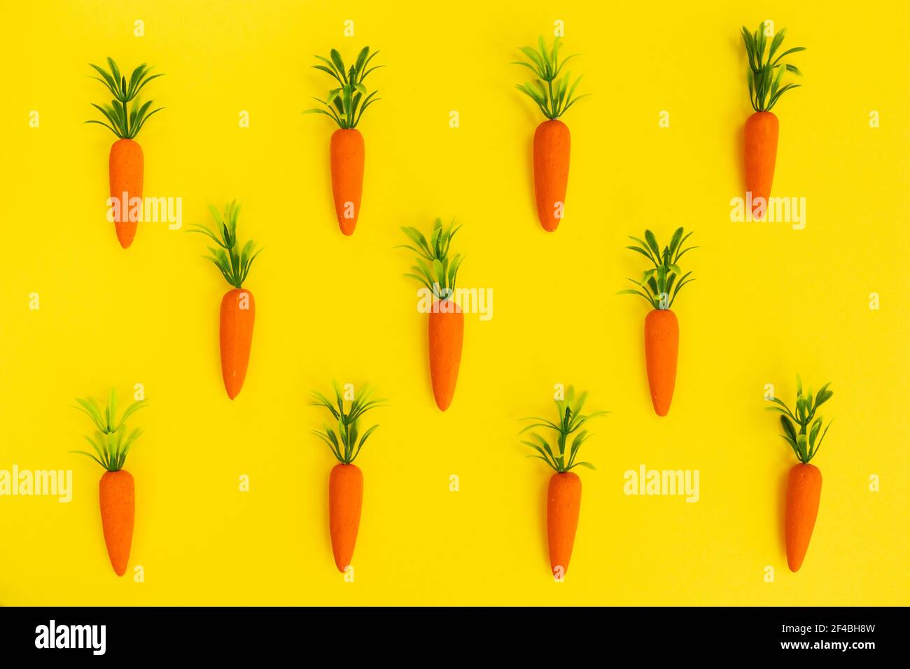 Easter pattern made with carrots on bright yellow background. Minimal Easter composition. Flat lay. Stock Photo