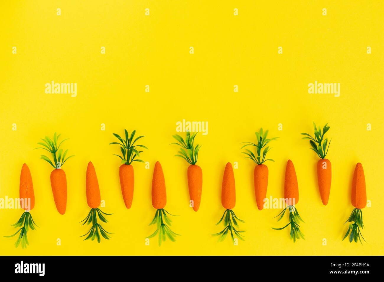 Easter pattern made with carrots on bright yellow background. Minimal Easter composition. Flat lay. Stock Photo