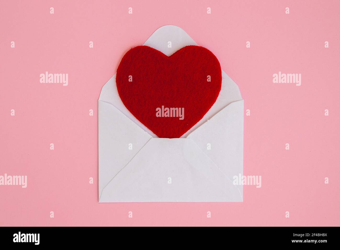 Open white envelope with big red heart on pink background. Love letter with heart. Valentine's, Mother, Women's day greetings. Stock Photo