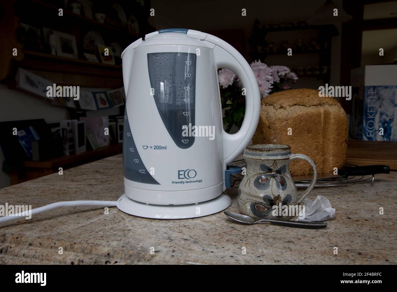 White eco friendly energy efficient kettle  on kitchen worktop with mug tea bag and fresh loaf of bread Stock Photo