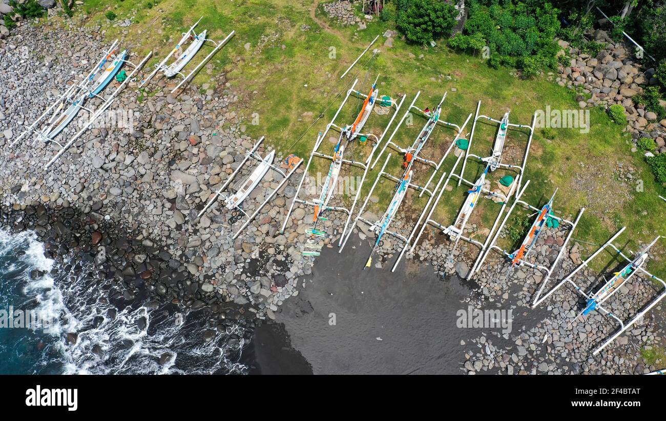 Top down aerial of traditional jukung boats resting on beach in Bali. Amed beach in Bali Indonesia with Jukung fishing boats lined up on the shore Stock Photo