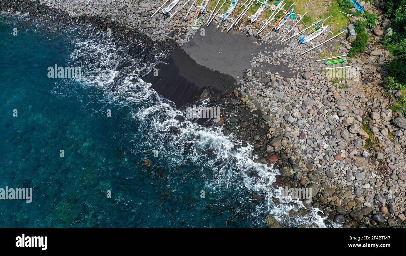 Top down aerial of traditional jukung boats resting on beach in Bali. Amed beach in Bali Indonesia with Jukung fishing boats lined up on the shore Stock Photo