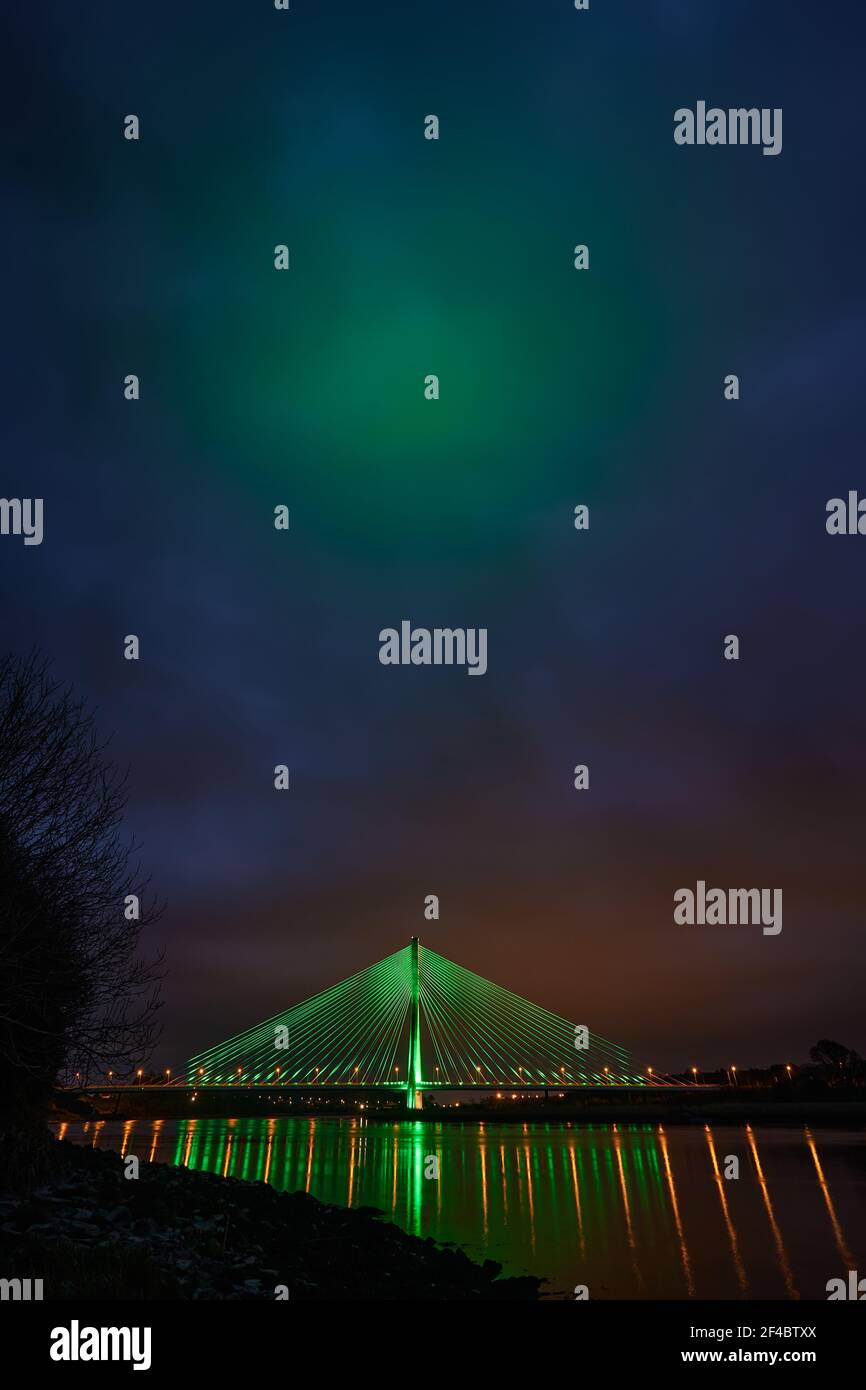 Modern line bridge illuminated with green lights for St. PAtricK in Waterford Ireland. Overnight. Stock Photo