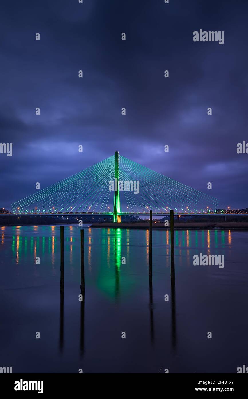 Modern line bridge illuminated with green lights for St. PAtricK in Waterford Ireland. Overnight. Stock Photo