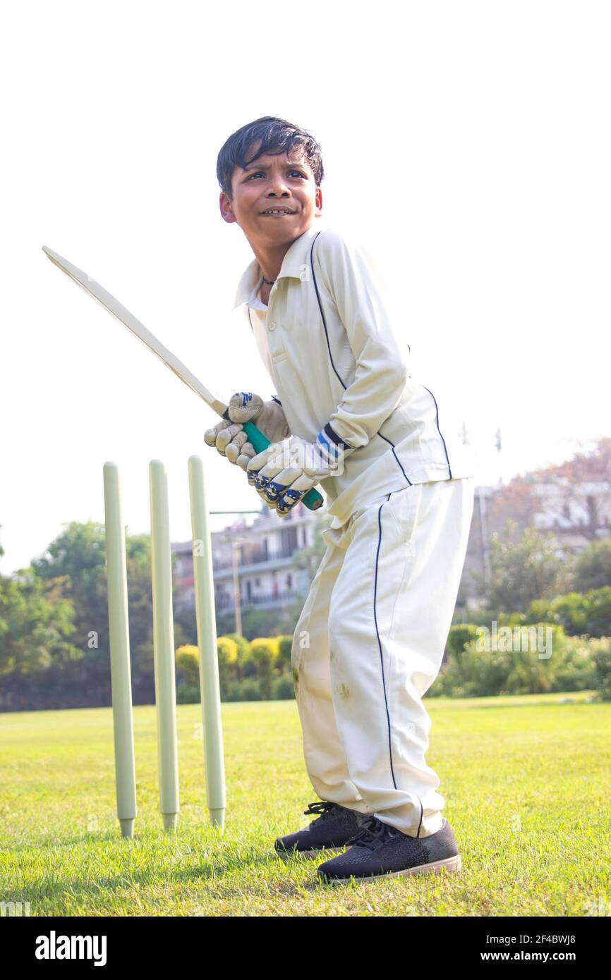 Young boy batting in protective gear during a cricket Stock Photo Alamy