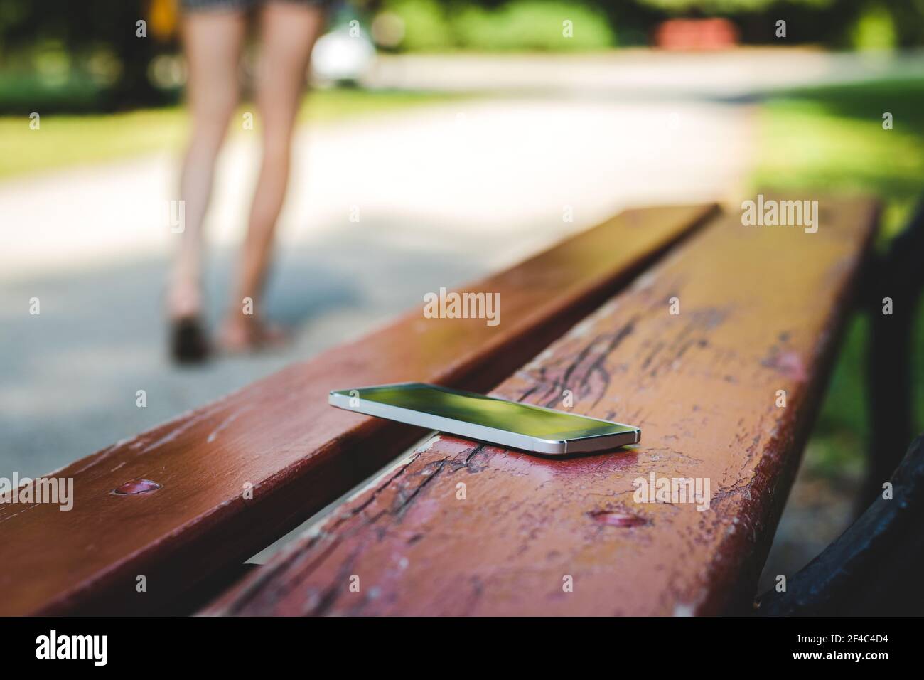 Lost smartphone on bench in public park. Woman leaving from bench whre she  forget her smart phone Stock Photo - Alamy