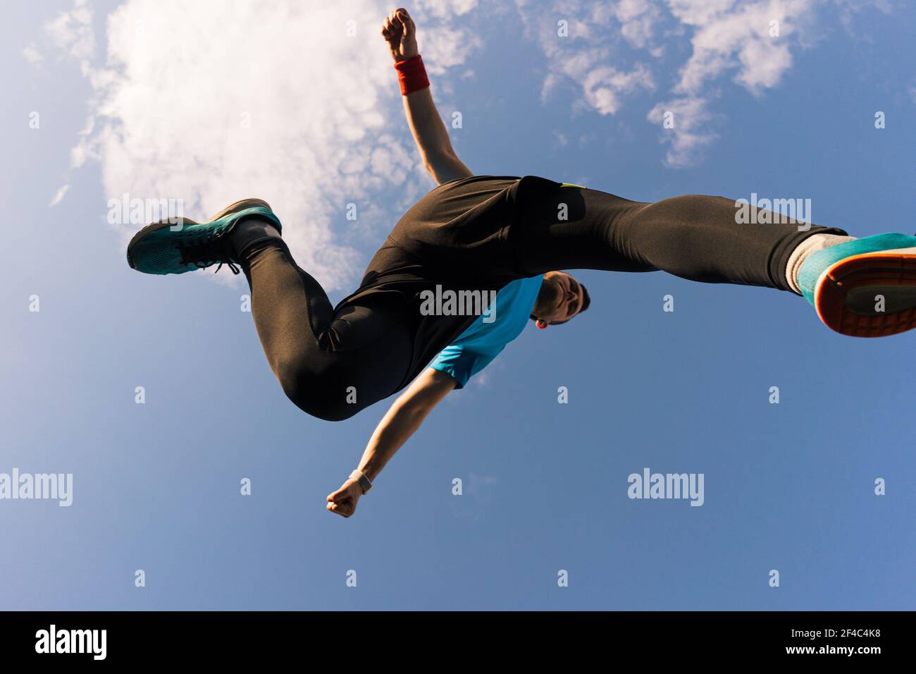 Low angle view of a sportsman who jump and run with blue sky in background Stock Photo